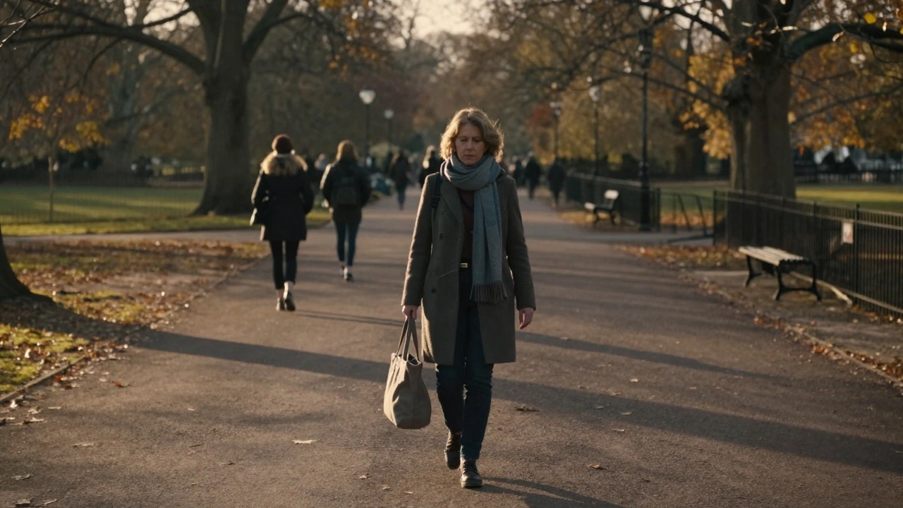 A woman walking alone through Hyde Park at sunset, autumn leaves falling around her.